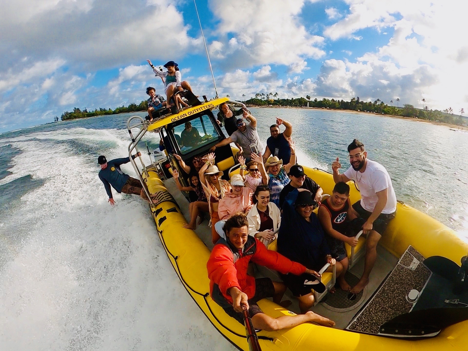 Group of people smiling on a yellow inflatable boat in the ocean.