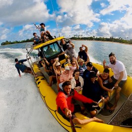 Group of people on a yellow speedboat, enjoying a sunny day on the water.