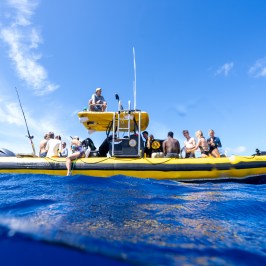 People on a yellow inflatable boat in the ocean under a clear blue sky.