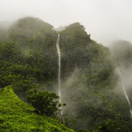 Foggy mountains with waterfalls cascading down lush green slopes.
