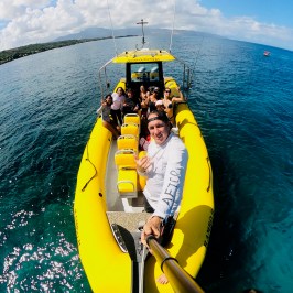 Group on a yellow boat in clear blue water under a sunny sky.