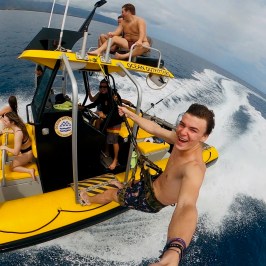 Group of people enjoying a yellow boat ride on the ocean, with one person taking a selfie.