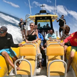People enjoying a boat ride on the ocean under a blue sky.