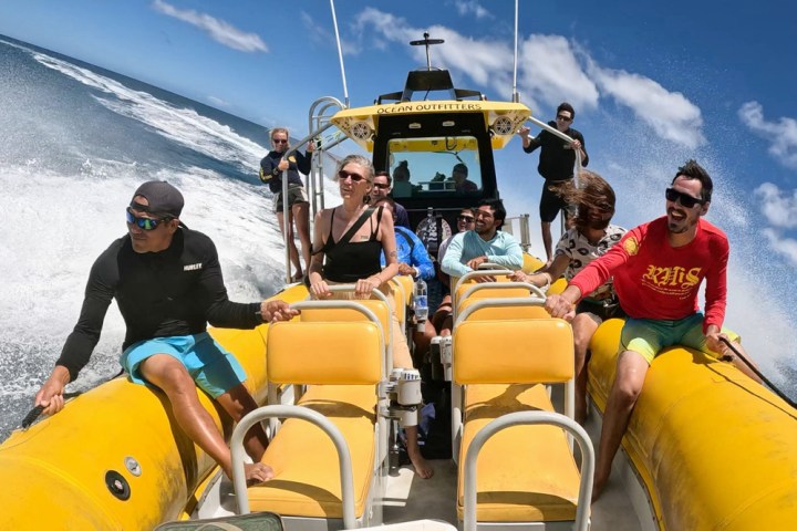 People enjoying a boat ride on the ocean under a blue sky.