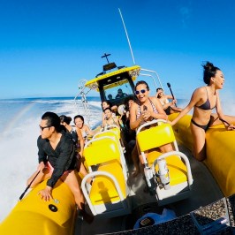 Group enjoying a speedboat ride on the ocean under a clear blue sky.