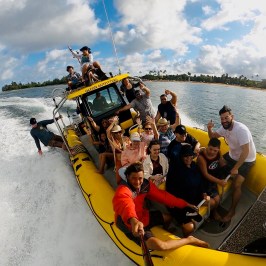 Group of people smiling on a yellow boat in the ocean.