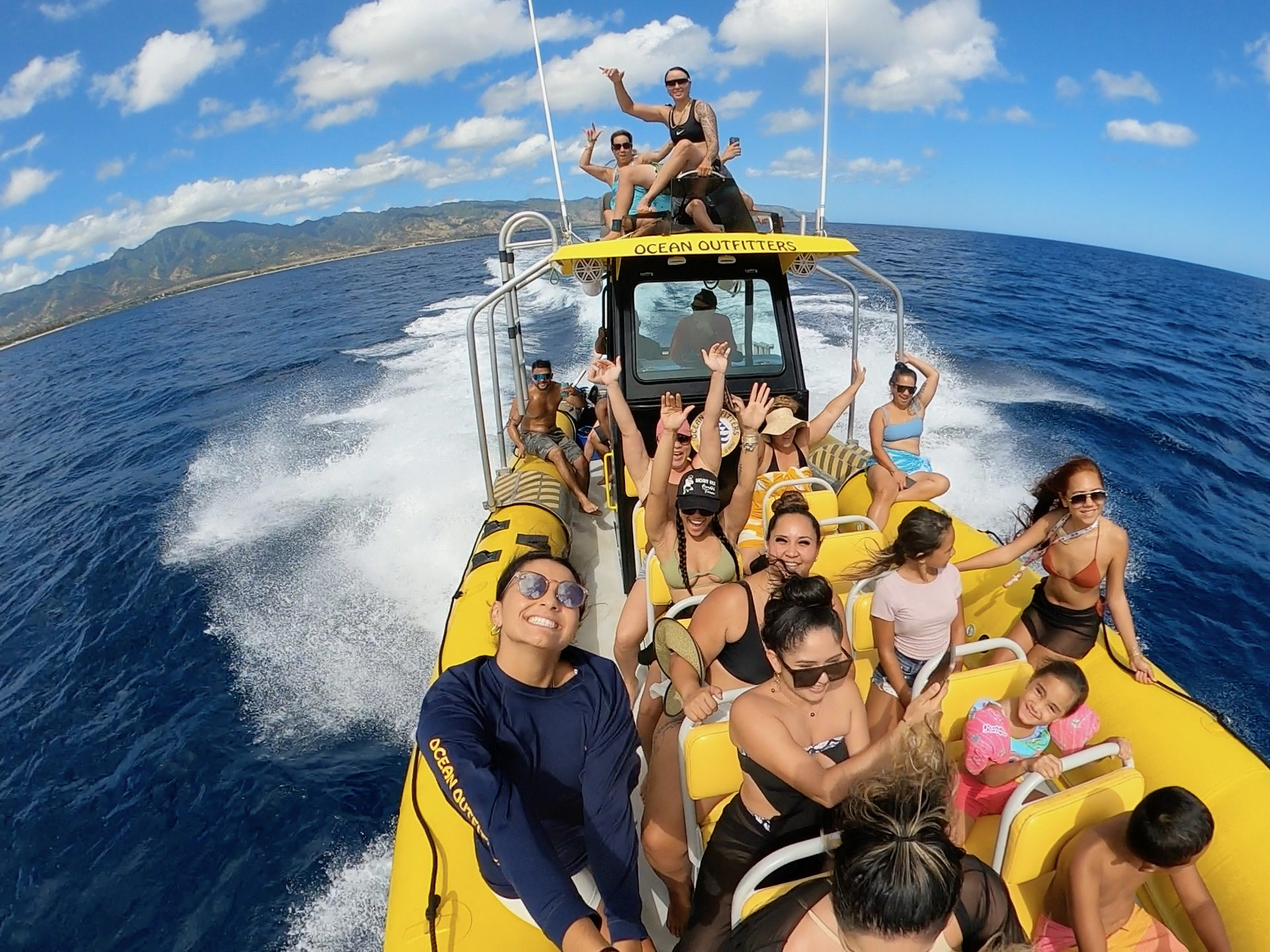 Group of people enjoying a boat ride on the ocean under a blue sky.