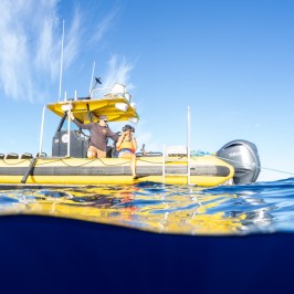 Person on a yellow boat floating on blue ocean under clear sky.