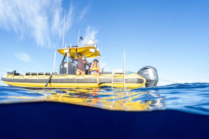Person on a yellow boat floating on blue ocean under clear sky.