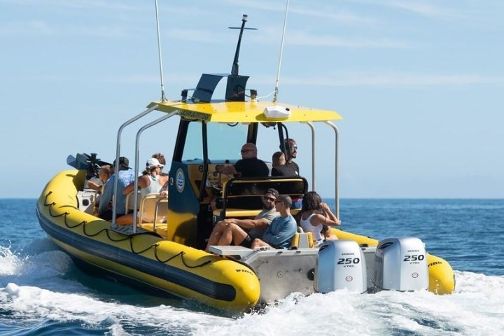 Yellow inflatable boat with six people cruising on the ocean.