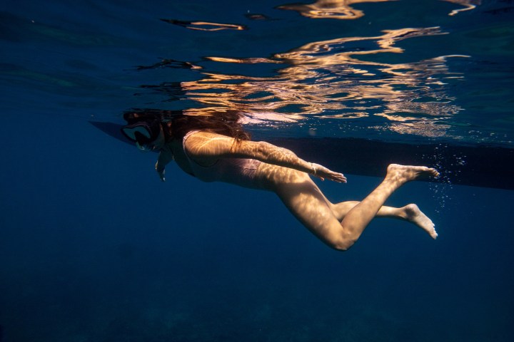 Person swimming underwater near the ocean surface.